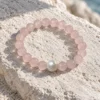 Blush Veil rose quartz and pearl bracelet resting on a pale textured rock