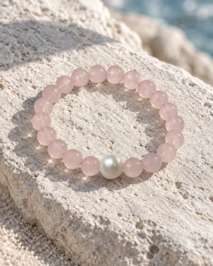 Blush Veil rose quartz and pearl bracelet resting on a pale textured rock
