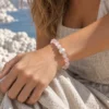 Close-up of the Blush Veil rose quartz and pearl bracelet worn against a beige dress