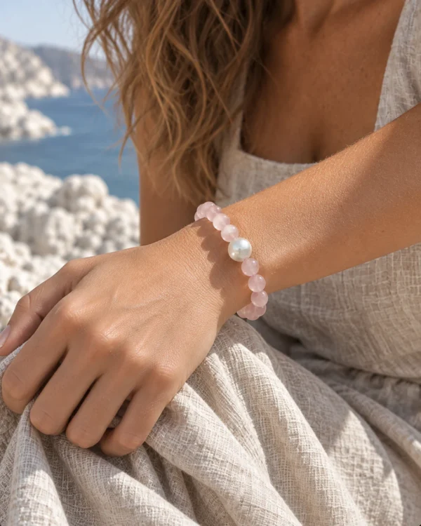 Close-up of the Blush Veil rose quartz and pearl bracelet worn against a beige dress
