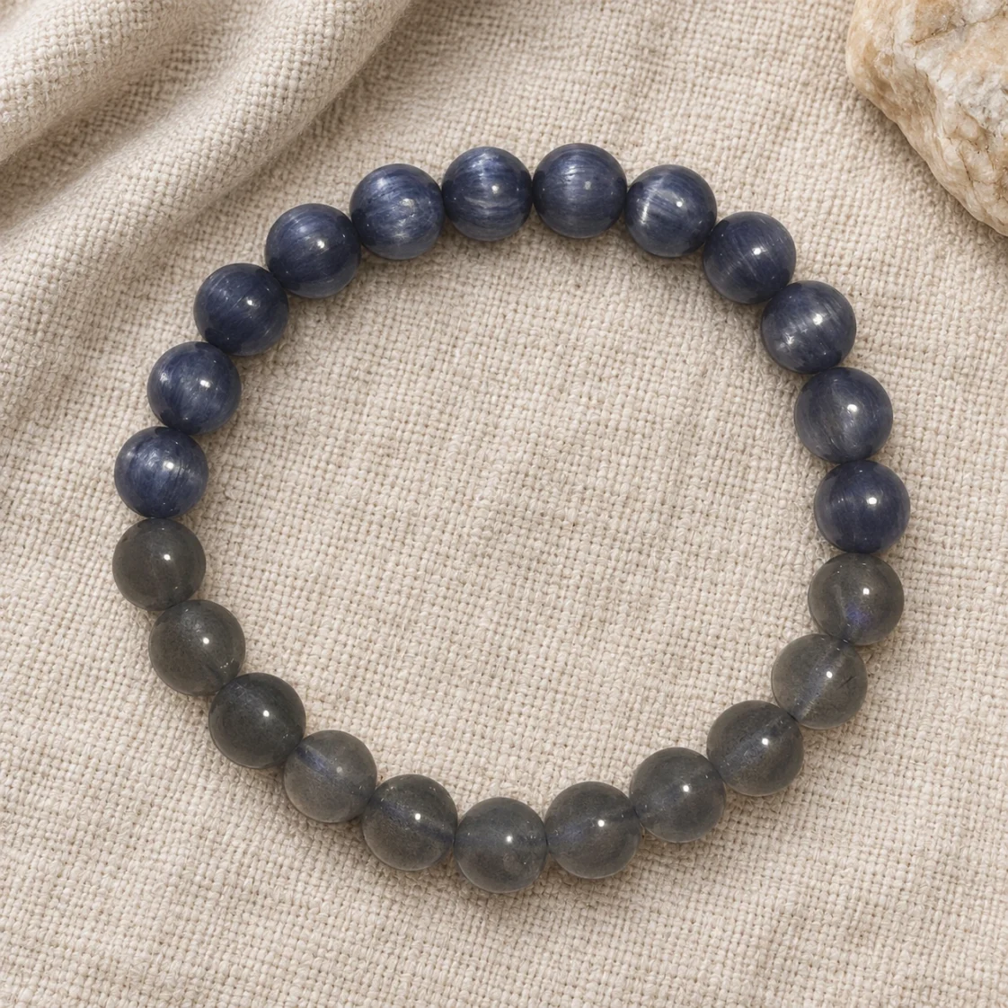 Dusk Meridian blue and grey stone bracelet on draped linen beside pale stone