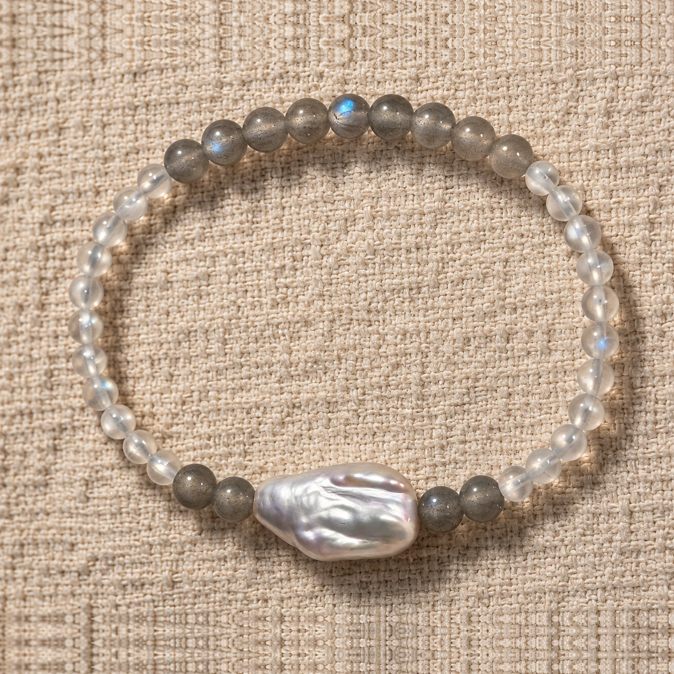 Pale Orbit moonstone bracelet on linen with its baroque freshwater pearl at the bottom center