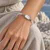Close-up of the Pale Orbit moonstone and pearl bracelet worn against a beige dress