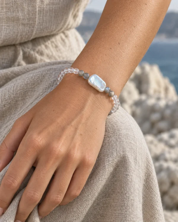 Close-up of the Pale Orbit moonstone and pearl bracelet worn against a beige dress