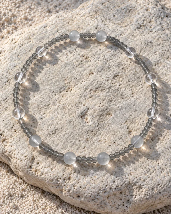 Quiet Orbit quartz and blue moonstone bracelet arranged on a sunlit pale rock