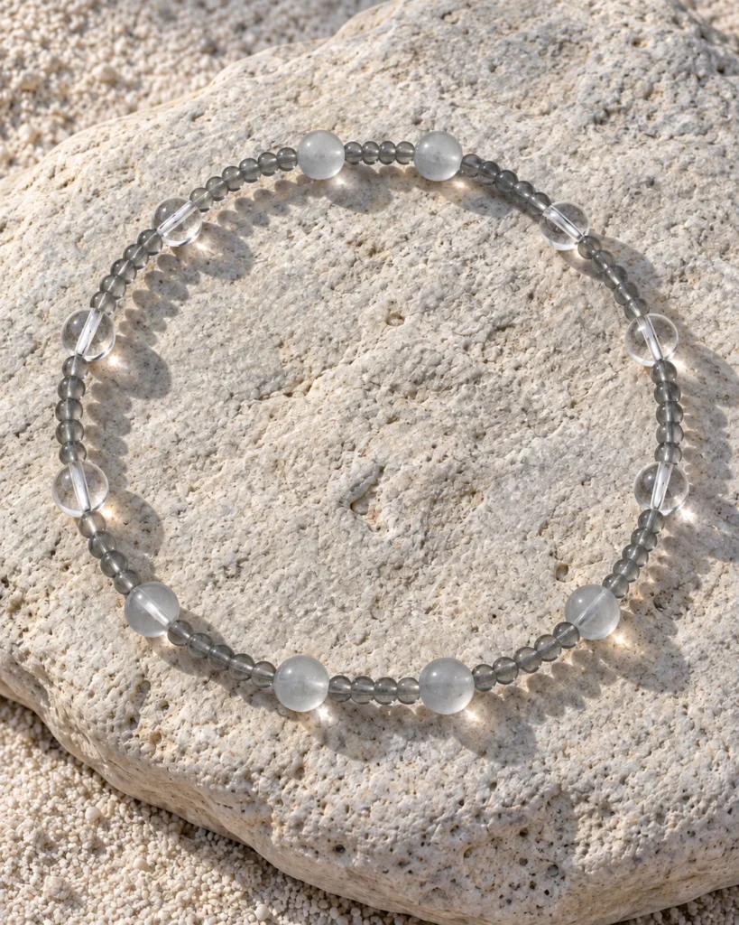 Quiet Orbit quartz and blue moonstone bracelet arranged on a sunlit pale rock
