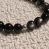 Close-up of Silver Nocturne obsidian, silver sheen obsidian and a sterling silver accent on woven fabric