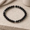 Silver Nocturne obsidian and sterling silver bracelet on pale stone beside linen