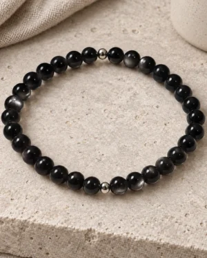 Silver Nocturne obsidian and sterling silver bracelet on pale stone beside linen