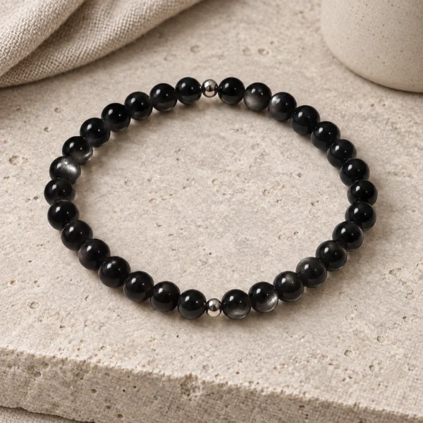 Silver Nocturne obsidian and sterling silver bracelet on pale stone beside linen