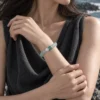 Close-up of the Tidal Glass green fluorite bracelet worn with a charcoal sleeveless top