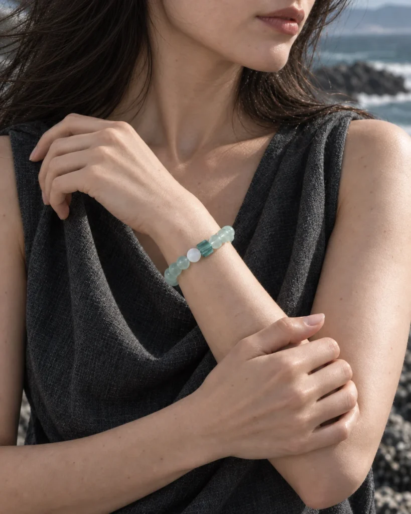 Close-up of the Tidal Glass green fluorite bracelet worn with a charcoal sleeveless top